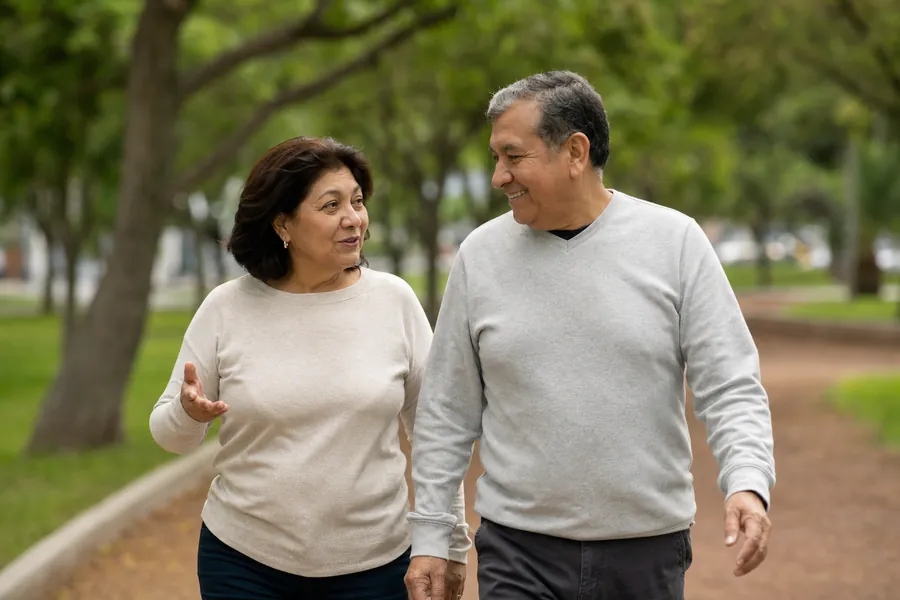 Pareja peruana de unos 58 años caminando sin dolor por un parque de Lima después del tratamiento con Fleko